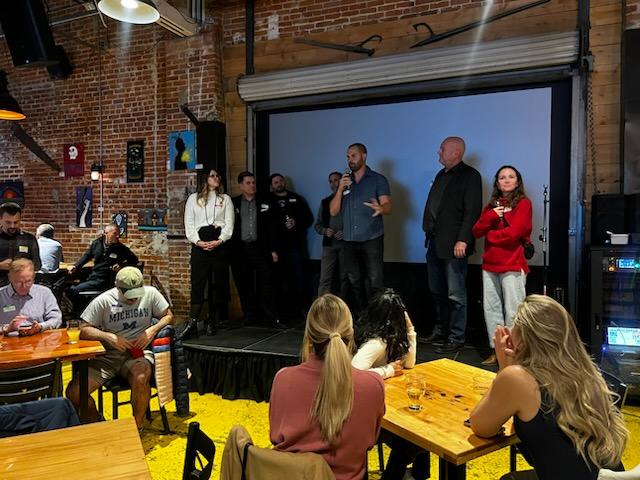A speaker addressing the crowd on stage at a Boulder Tech Connect networking meetup